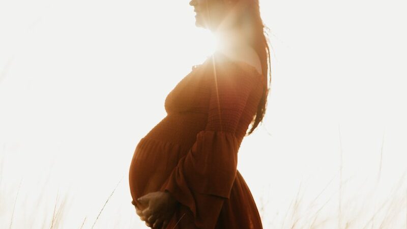 A pregnant woman outdoors at sunset